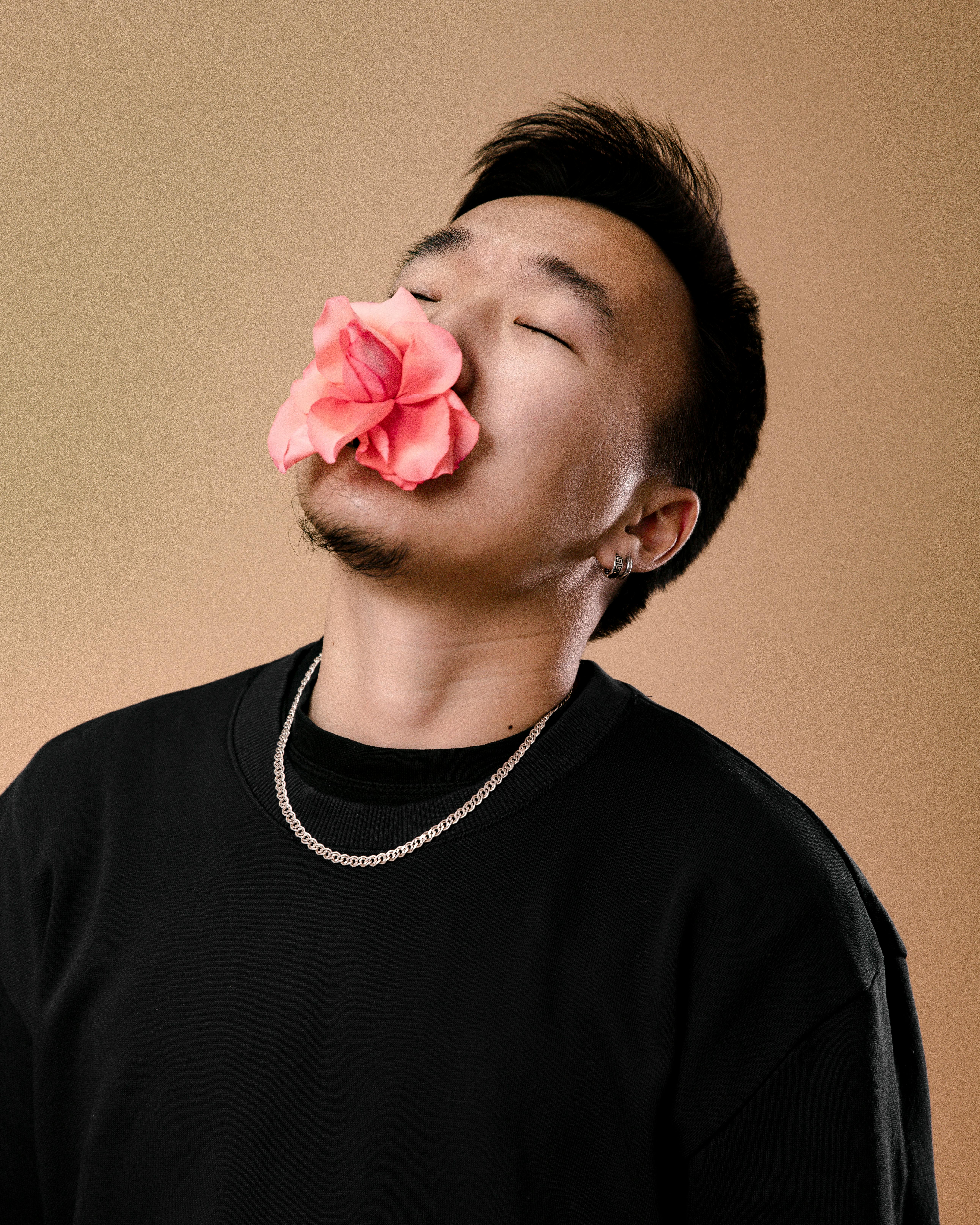 Artistic portrait of a man with closed eyes and a rose in his mouth