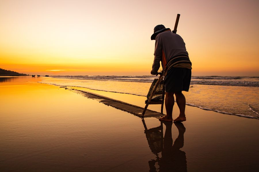 Traditional fisherman casting a net on Ho Tram Beach at sunset
