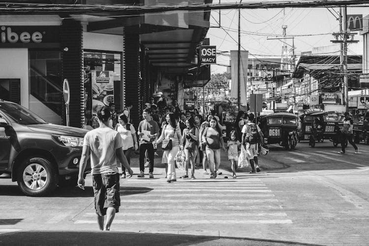 Monochrome Photography Of People Crossing The Road