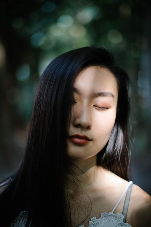 Free A serene portrait of a woman with eyes closed, captured with gentle light and shadow play. Stock Photo