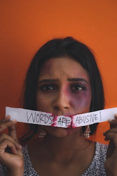 A woman with a concerned expression holds a message about verbal abuse against an orange background.