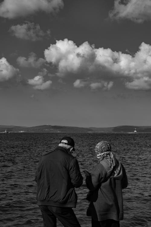A Couple Near a Body of Water Under a Cloudy Sky