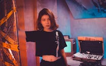 室内有一幅喜怒无常的亚洲女性肖像，旁边放着老式电视和警示胶带