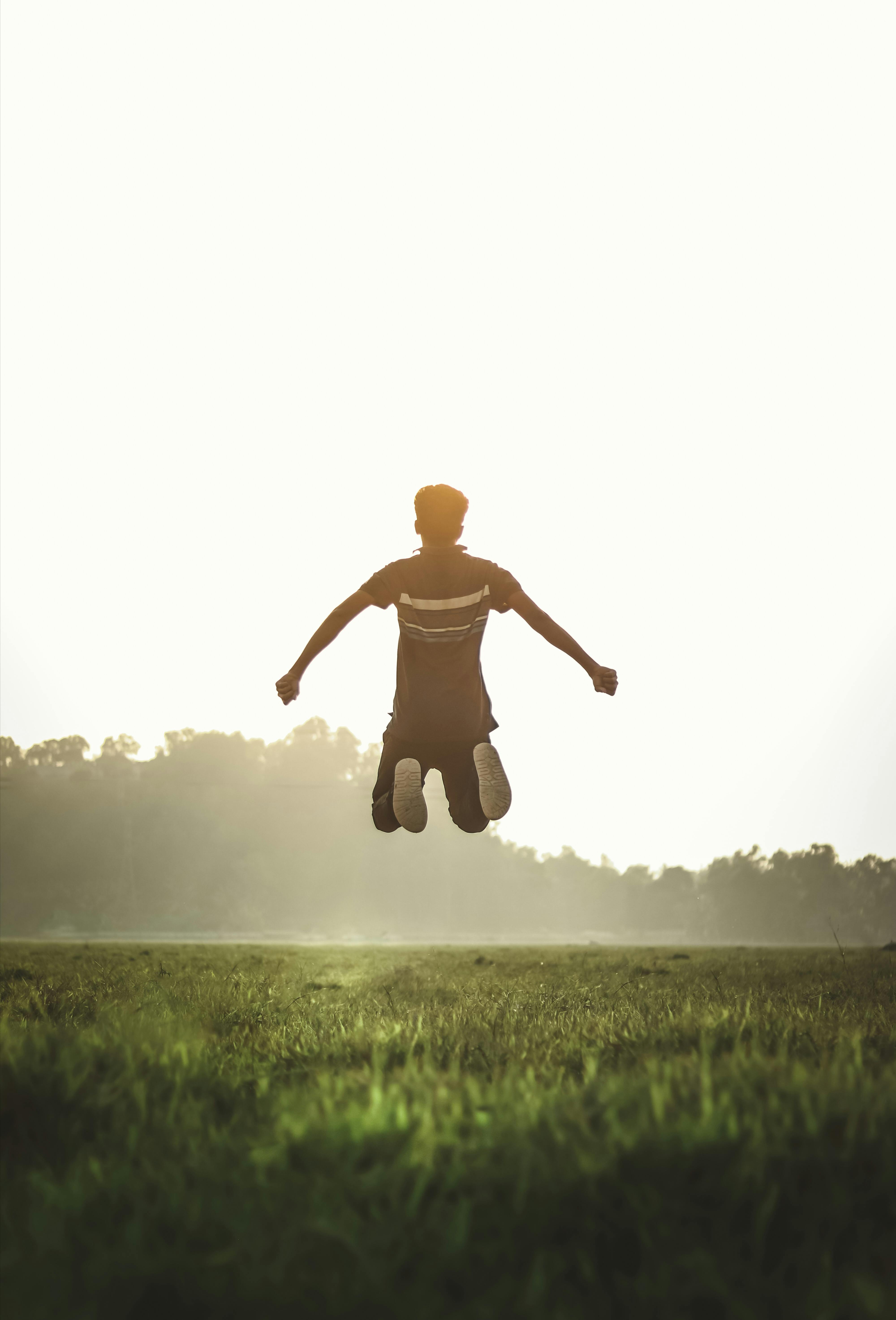 man wearing polo shirt jumping on green grass field