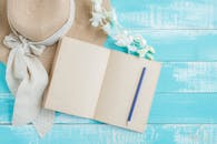 一间创意公寓里，蓝色木制表面放着一顶草帽、一本空白笔记本和一支铅笔