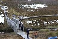 白雪皑皑的风景中，游客们走在木桥上