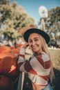 Portrait of Smiling Woman Leaning at Wooden Cart Full of Pumpkins