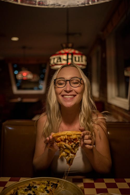 A Woman in Eyeglasses Holding a Pizza