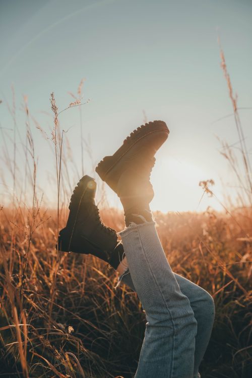 Free Stylish black boots against a stunning sunset in an open field, exuding a sense of freedom. Stock Photo