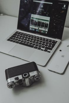 Vintage analog camera with a modern laptop and smartphone on a desk.