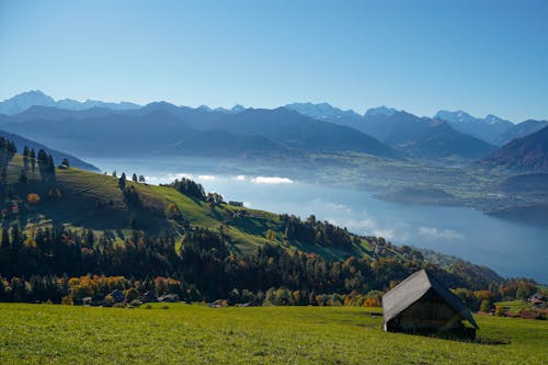 Free Brown Wooden House on Green Grass Field Near Mountains Stock Photo