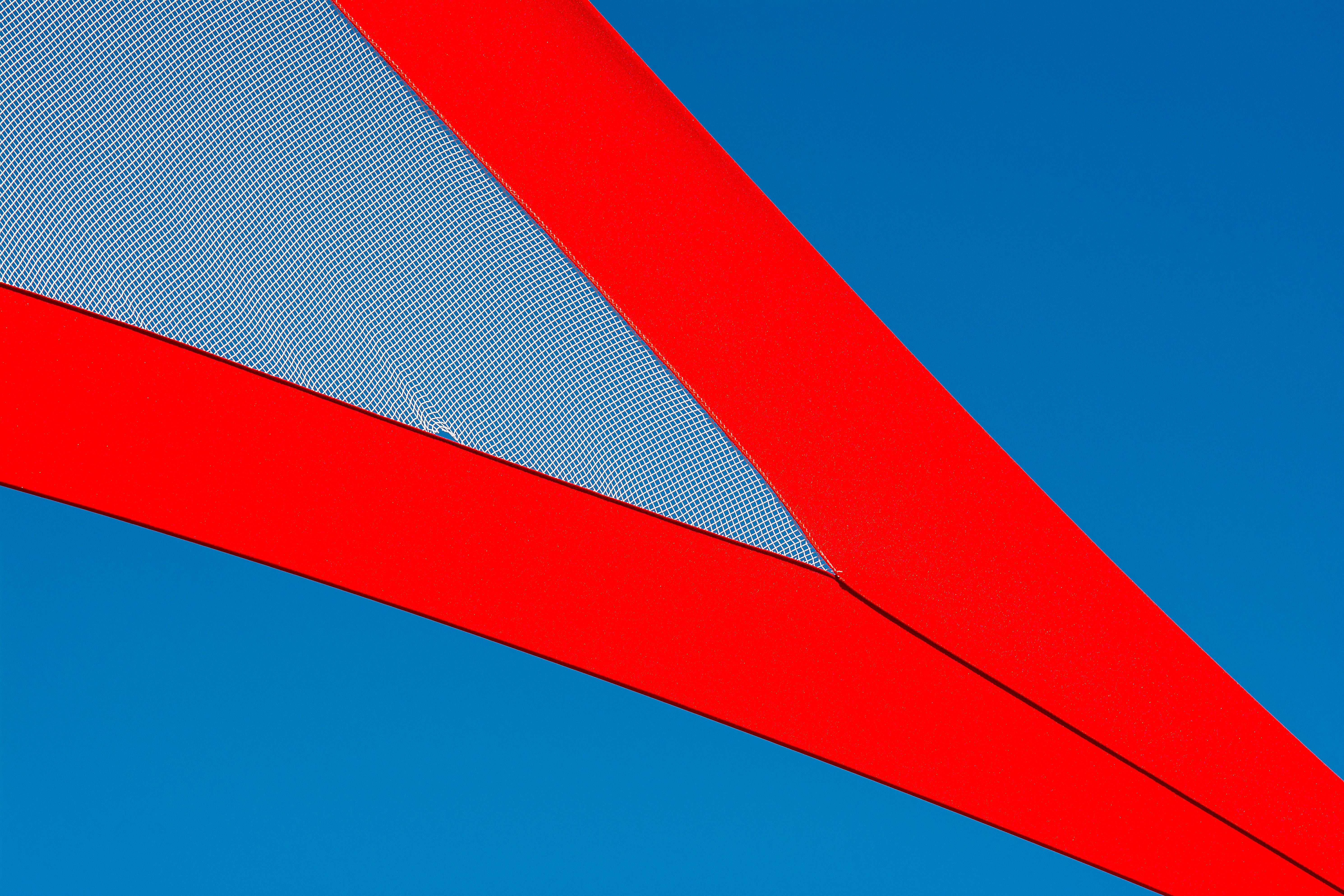 Close-up of a modern abstract structure with bold red and blue geometry against a clear sky.