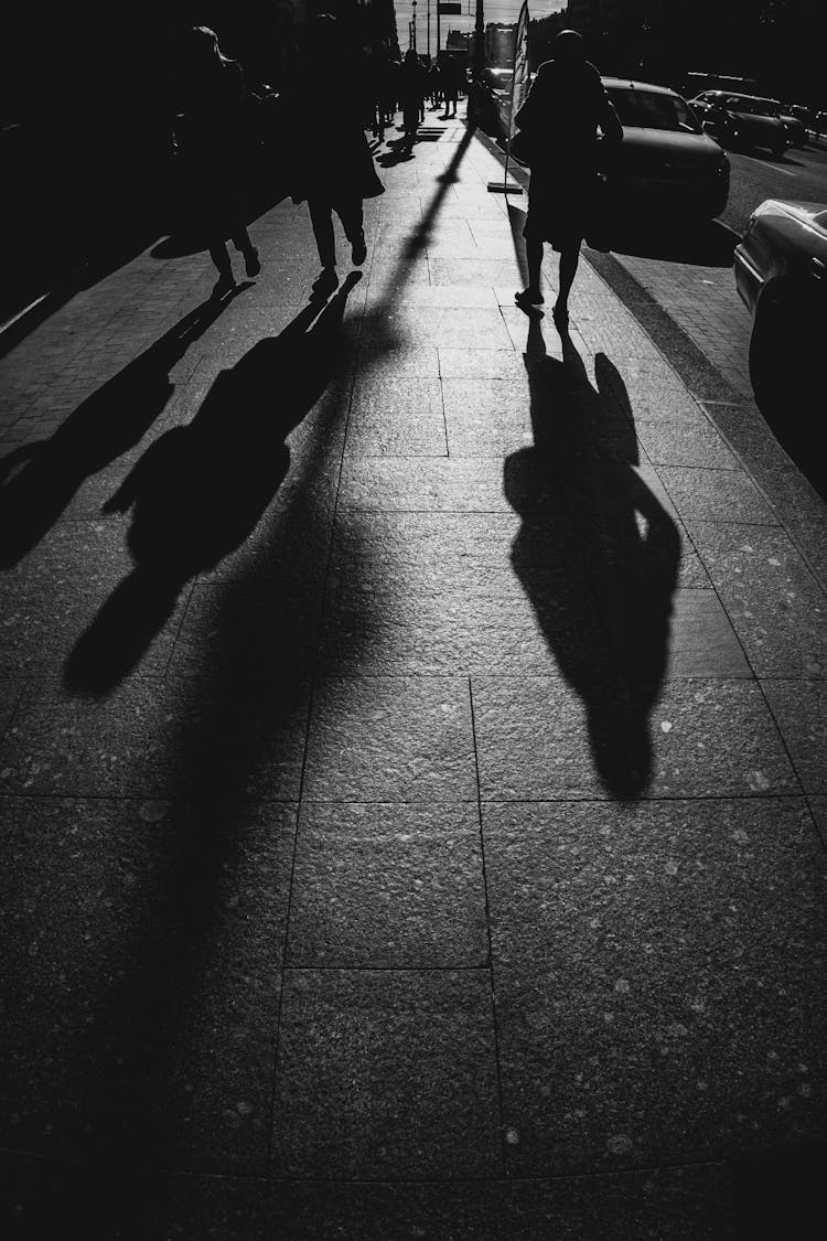 Shadows Of People Walking On Sidewalk On City Street