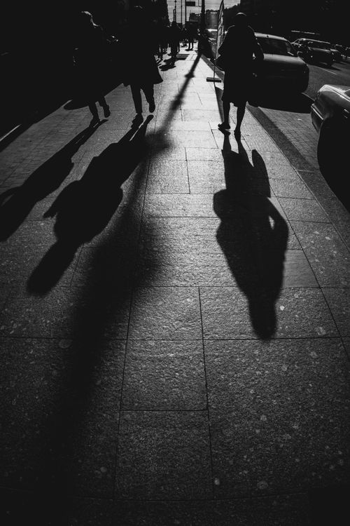 Free Silhouetted figures and shadows on a city street create a striking, dramatic scene. Stock Photo
