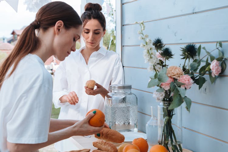 Two Women Arranging Fruits And Bread On Table