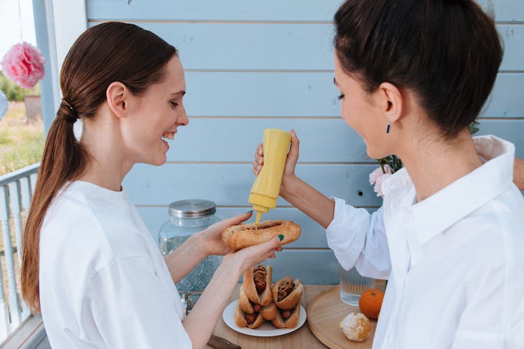 Women Putting Mustard On Hotdog Sandwich