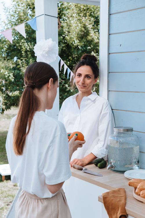 Free Two women enjoying a casual outdoor gathering with drinks and snacks. Stock Photo