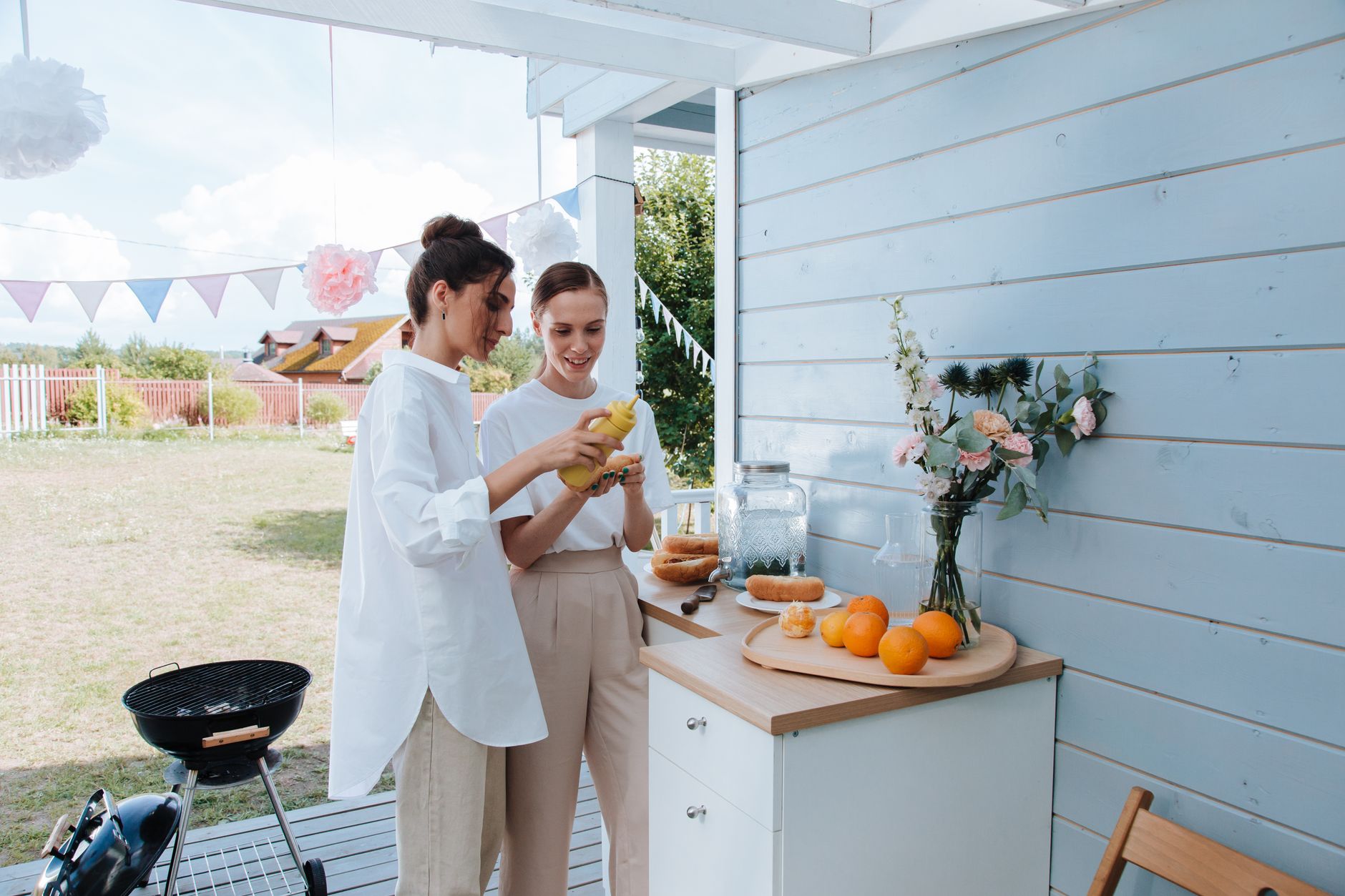 Two women preparing food outdoors for a summer barbecue celebration.