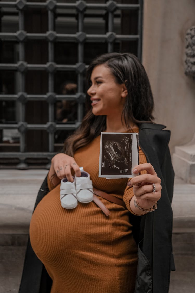 Pregnant Woman With Picture Of Baby And Shoes