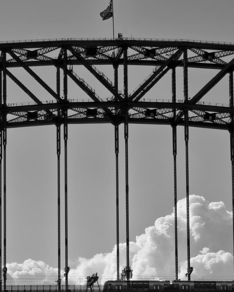 Grayscale Photo Of A Flag On Top Of Sydney Harbour Bridge