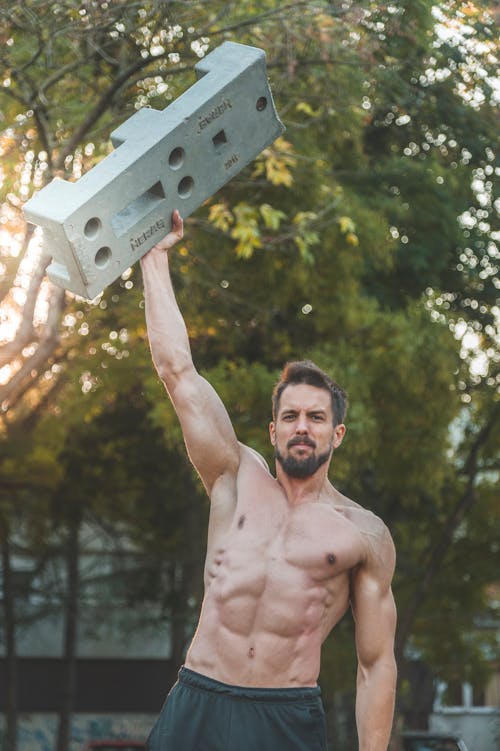 Muscular Man Holding a Concrete Block 