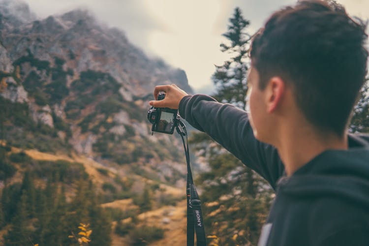 Man Taking Picture In Mountains With Camera