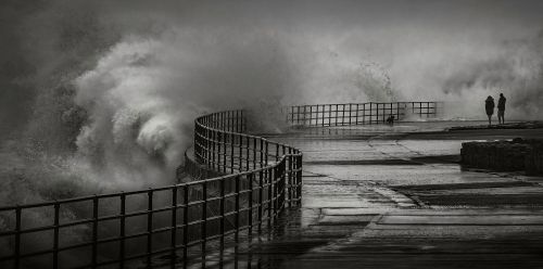 Free Powerful crashing waves at Whitley Bay in a dramatic black and white scene with people observing. Stock Photo