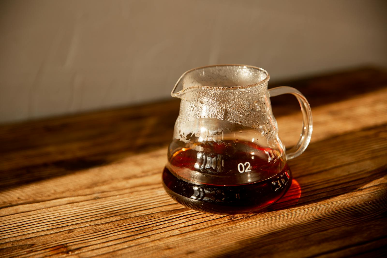 Fresh drip coffee in glass server on a wooden table