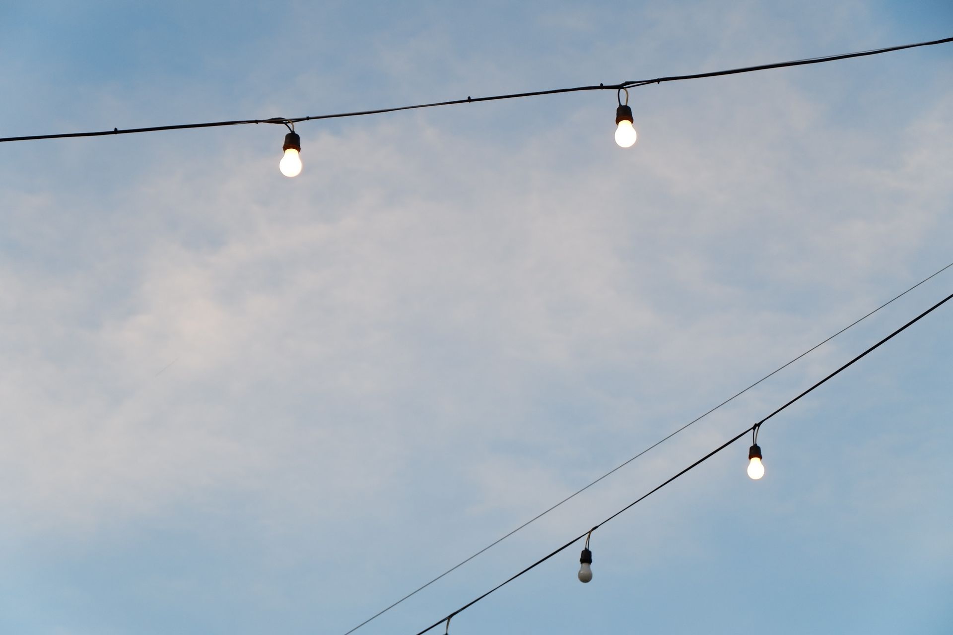 Minimalist outdoor scene of string lights against a blue sky, capturing a peaceful atmosphere.