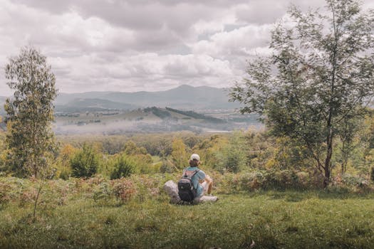 A backpacker enjoying a scenic landscape in Gruyere, VIC, Australia, with rolling hills and a cloudy sky.