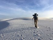 在晴朗的天空下，一名孤独的徒步旅行者穿越白沙国家公园的白色沙丘