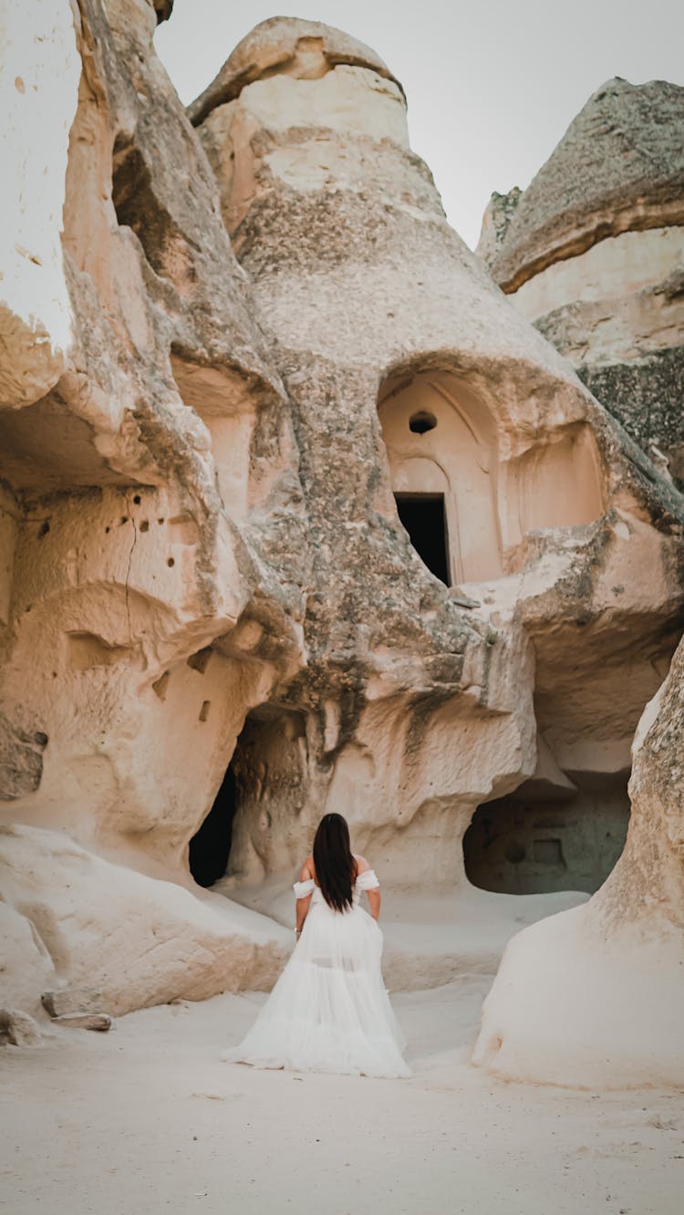 A Back View Of A Bride Walking Among Sand Caves