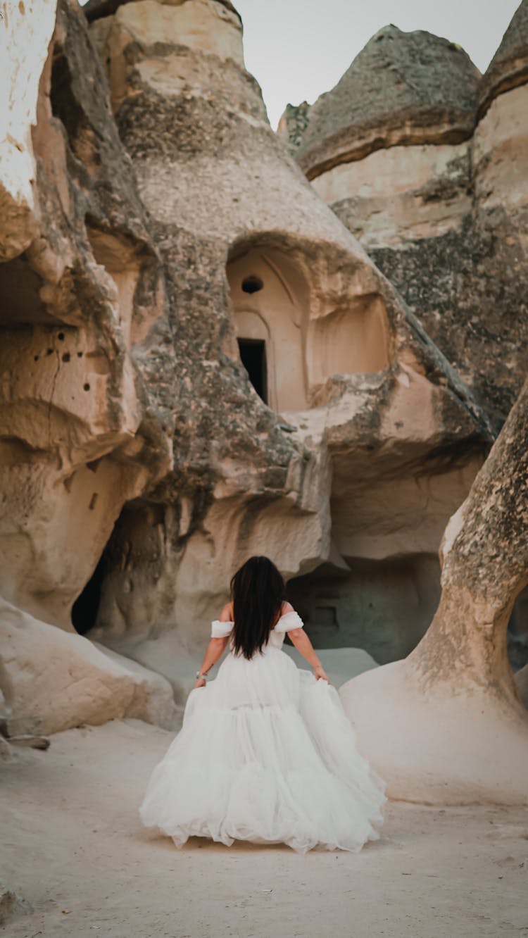 A Back View Of A Bride Walking Among Sand Caves