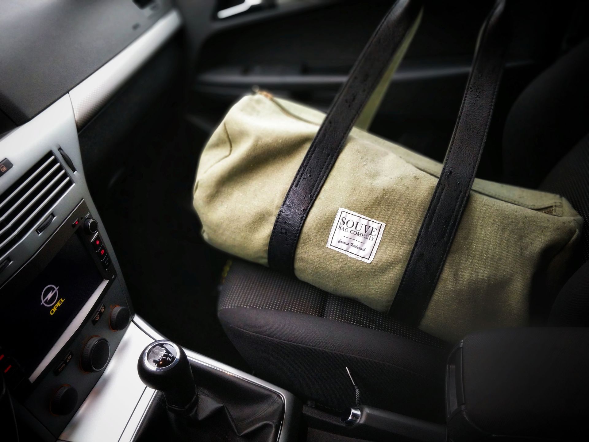 Stylish green canvas bag on a car seat displaying elegance and luxury travel.