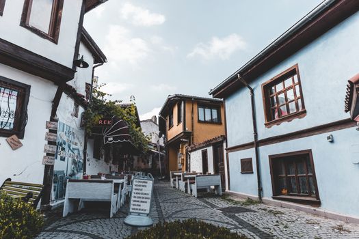 Charming street with cobblestone path and traditional houses under blue sky in historic town.
