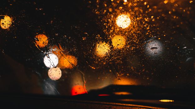 Abstract view of rain on a window with blurred lights creating a moody atmosphere.