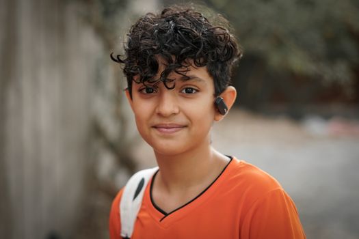 Boy in Orange Shirt Smiling at the Camera
