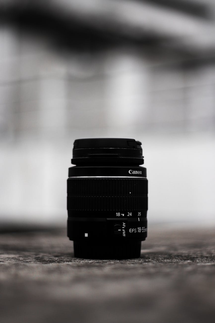 Detailed view of a Canon camera lens with blurred background, showcasing photography equipment.