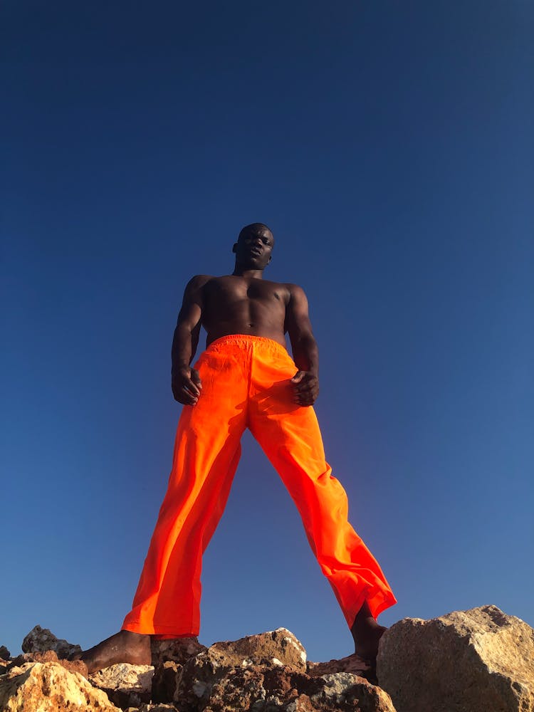 Man In Neon Orange Pants Standing On Rocks