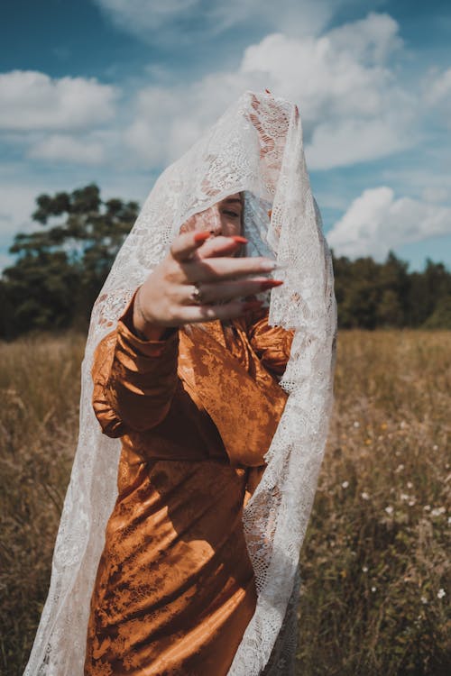 Person in Brown Long Sleeve Dress Holding White Textile