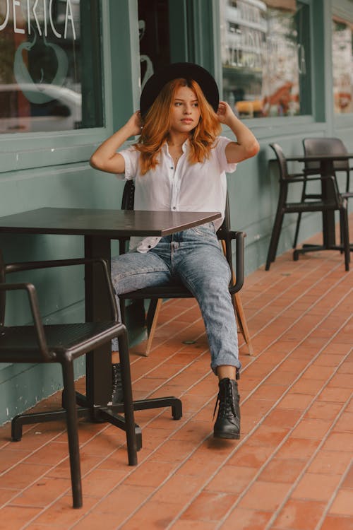 Free 
A Woman Wearing a Black Hat and Denim Pants Sitting Stock Photo
