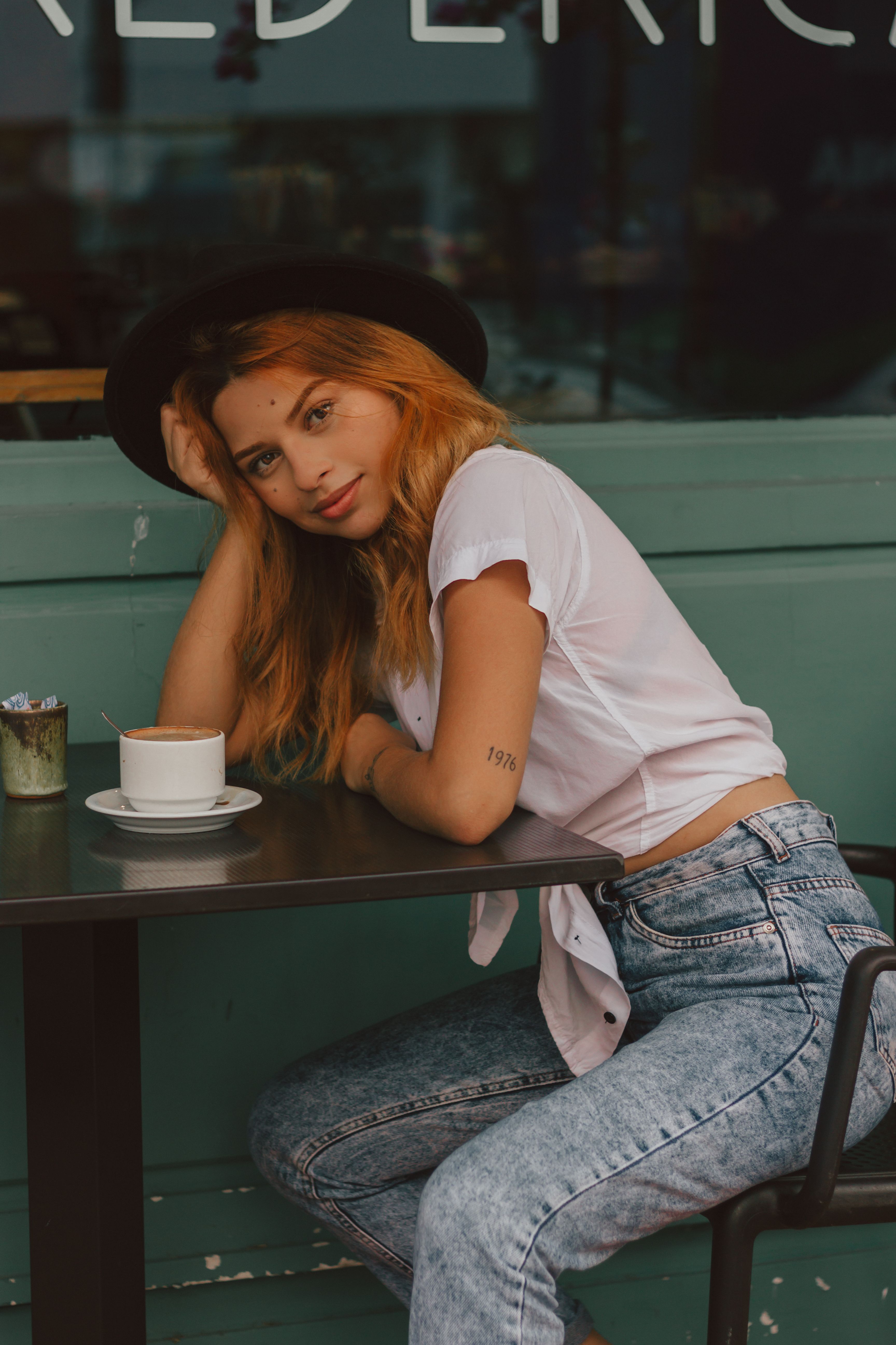 A Woman in White Crop Top and Blue Denim Jeans Sitting on Concrete Wall ...