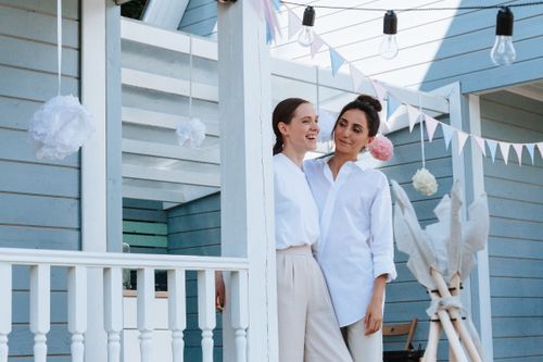Free Smiling couple embraces under festive decorations on a sunlit porch, exuding happiness and love. Stock Photo