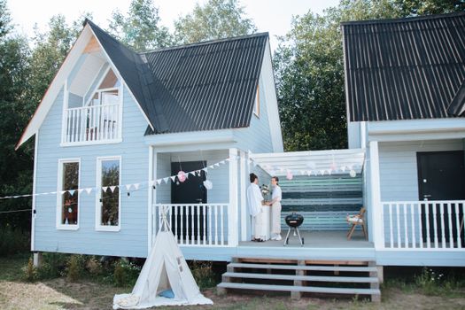 Two Women Standing in a Patio of a Blue Wooden House