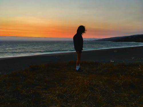 日没時に海岸に立っている人