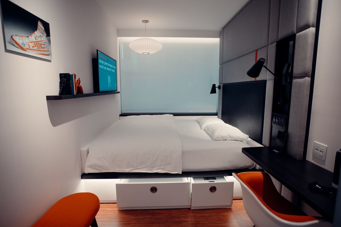 Quarto compacto com cama elevada e gavetas de armazenamento abertas na base