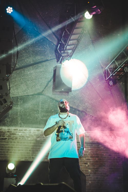 Free Bearded man performs energetically on stage under dramatic lights, holding a microphone. Stock Photo