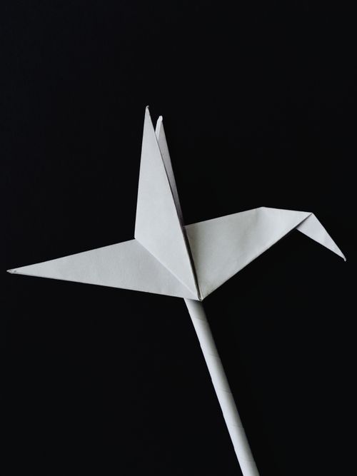 Free Close-up of a white origami crane against a black backdrop. Stock Photo