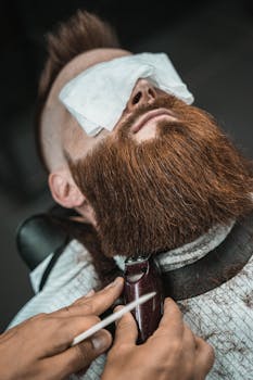 Close-up of a man's beard being trimmed by a barber in a barbershop setting.