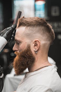 Side view of a bearded man receiving a haircut in a modern barbershop setting.